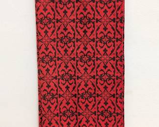 A red scarf with black printed medieval-style floral pattern