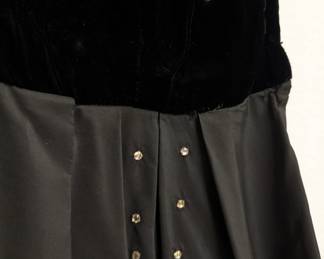 Closeup of vintage 1950s black cocktail dress featuring a velvet bodice and a full taffeta skirt with rhinestone accents