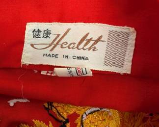 Closeup of vintage red kimono robe dressing gown with embroidered pavilion landscapes on the pockets and embroidered dragon over landscape on the back