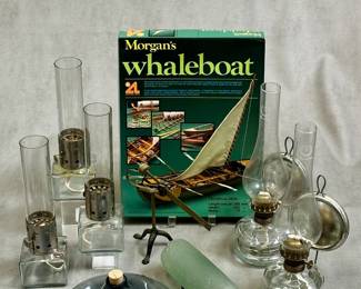 A set of three vintage kerosene lanterns with square glass bases, metal burners and cylindrical glass chimneys; a Morgan's Whaleboat model ship kit by Artesania Latina, an antique brass postal letter scale, antique glass bottles, and a pair of kerosene or paraffin lamps with glass bodies and chimneys and attached metal reflector attached to a wall bracket. 