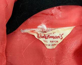 Closeup of vintage coral or reddish-orange color robe made in Japan, with floral pattern embroidery and white piping along the collar, cuffs, and pockets