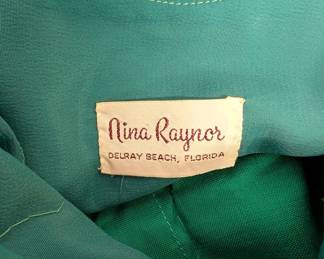 Closeup of vintage Nina Raynor party dress in vibrant emerald green, with scoop neck ruched bodice, cap sleeves, ribbon belt and a floaty full skirt.