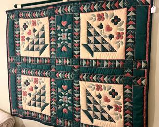 Handmade quilt featuring basket and floral patterns, displayed as a wall hanging
