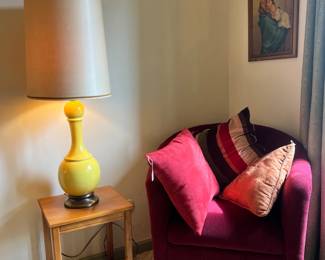 Deep berry-colored swivel club chair, a mid-century wood side table, and a bright yellow "pop of color" table lamp