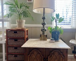 marble-top cabinet table paired with an oversized mid-century brass ball lamp and wicker storage tower