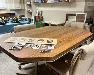 Octagonal wood-grain laminate table with four upholstered brass-frame chairs on rolling casters