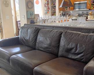 Brown leather sofa with nailhead trim, view of dining room