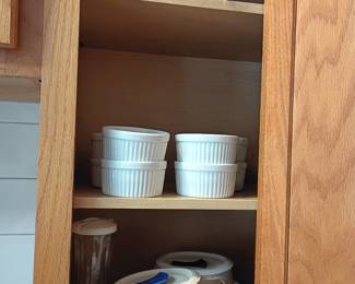 Kitchen cabinet with white ramekins and pitcher