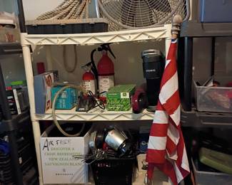 Garage storage shelf with box fan, American flag, and household items