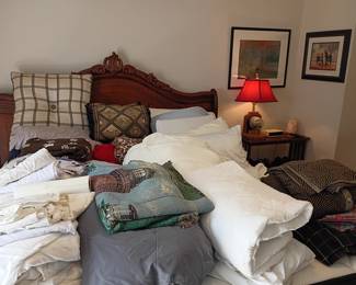 Carved wood bed with linens, blankets, and pillows