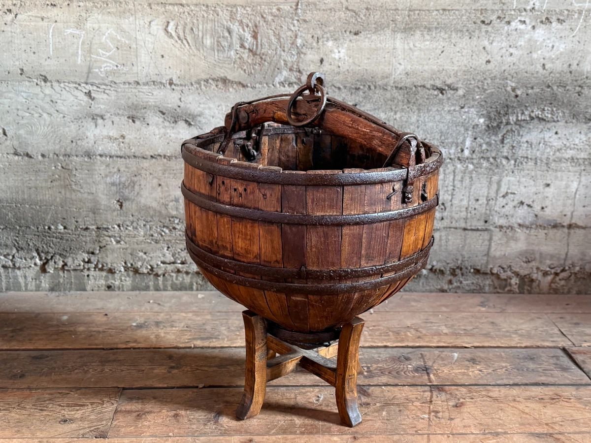 An antique Chinese wooden water bucket with stand. Features incredible patina through and well made. Measures on stand, 24” H x 18” W x 18” D.