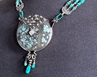 Multi-strand necklace with turquoise and silver beads featuring a large sterling silver pendant with intricate turquoise inlay and decorative elements, including hanging charms. Marked ‘925’ for sterling silver purity. This necklace measures, 19.5” and has a total approx. weight of 205.91 grams.