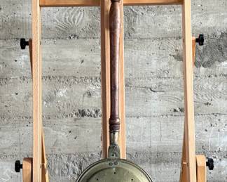 Brass bed warmer with floral etching and decorative perforations on the lid. The piece features a wooden turned handle with a rich patina and a hinged lid. The brass showcases signs of use with wear and age-related patina. The perforations were traditionally used for dispersing heat by placing warm materials inside the bed warmer. Suitable for collectors or historical display.