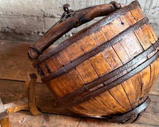 An antique Chinese wooden water bucket with stand. Features incredible patina through and well made. Measures on stand, 24” H x 18” W x 18” D.