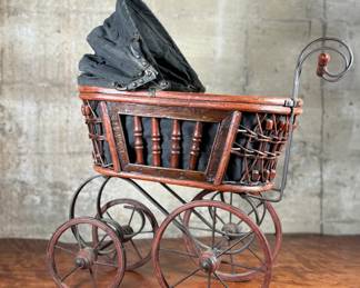 This lot features a beautiful antique Victorian-style doll carriage made from wicker, wood, and metal. This piece measures, 17.5” H x 19” W x 7” D.