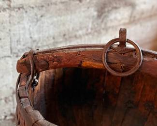 An antique Chinese wooden water bucket with stand. Features incredible patina through and well made. Measures on stand, 24” H x 18” W x 18” D.