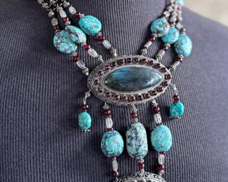 Sterling silver statement necklace featuring an intricate design with various gemstones. The hallmark ‘925’ is stamped on the reverse side, affirming its sterling silver composition. The piece includes multiple strands and pendants accented with gemstones. In good condition and designed with a secure clasp for wearability. This necklace measures, 18” with a total approx. weight of 356.22 grams.