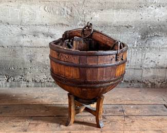 An antique Chinese wooden water bucket with stand. Features incredible patina through and well made. Measures on stand, 24” H x 18” W x 18” D.