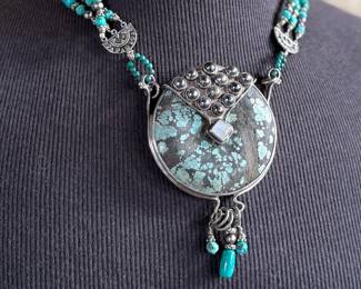 Multi-strand necklace with turquoise and silver beads featuring a large sterling silver pendant with intricate turquoise inlay and decorative elements, including hanging charms. Marked ‘925’ for sterling silver purity. This necklace measures, 19.5” and has a total approx. weight of 205.91 grams.