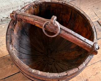 An antique Chinese wooden water bucket with stand. Features incredible patina through and well made. Measures on stand, 24” H x 18” W x 18” D.