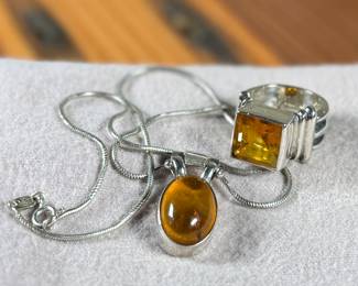 This lot features a stunning ring and necklace made from sterling silver and featuring amber center stones. The ring comes in a size 7 and the chain measures, 17”. Both items have a total approx. weight of 25.00 grams.