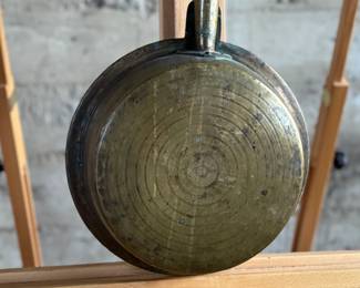 Brass bed warmer with floral etching and decorative perforations on the lid. The piece features a wooden turned handle with a rich patina and a hinged lid. The brass showcases signs of use with wear and age-related patina. The perforations were traditionally used for dispersing heat by placing warm materials inside the bed warmer. Suitable for collectors or historical display.