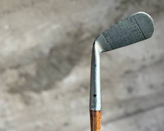 A vintage Frank Bryan Special Mashie golf club featuring a steel head and a wooden shaft. The head is marked with branding and includes the inscription ‘Special Mashie.’ The club has a textured steel clubface and a leather-wrapped grip, showing signs of wear consistent with use and age.