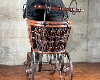 This lot features a beautiful antique Victorian-style doll carriage made from wicker, wood, and metal. This piece measures, 17.5” H x 19” W x 7” D.