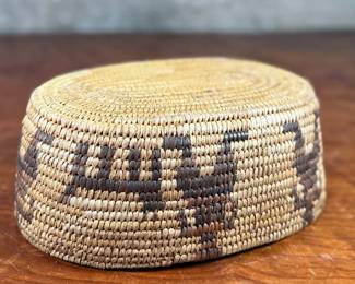 This lot features a stunning Native American basket, likely from the 1920s-1930s, made from heavy woven grass. This basket measures 3.75” H x 9.25” W x 6.5” D.