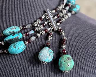 Sterling silver statement necklace featuring an intricate design with various gemstones. The hallmark ‘925’ is stamped on the reverse side, affirming its sterling silver composition. The piece includes multiple strands and pendants accented with gemstones. In good condition and designed with a secure clasp for wearability. This necklace measures, 18” with a total approx. weight of 356.22 grams.