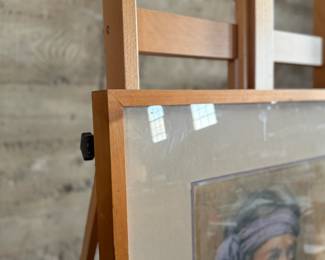 A framed painting depicting a portrait of a man wearing a purple headband. The artwork is signed ‘Rita’ in the lower right corner. The frame is wooden with a matte around the painting, and backed with paper that shows notable tearing. Frame is a bit loose. Measures in frame, 28” H x 23” W.