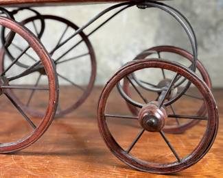 This lot features a beautiful antique Victorian-style doll carriage made from wicker, wood, and metal. This piece measures, 17.5” H x 19” W x 7” D.
