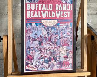 Framed posters advertising the Buffalo Ranch Real Wild West show. Printed by Riverside Print Co., Chicago, these posters feature vibrant depictions of cowboys, Native Americans, and historical scenes. The frames show some age-related wear, and the paper backing is partially torn, exposing an art gallery label from Hulmeville, Pennsylvania. One of them is protected by glass and the other is not. Each one measures in frame, 37” H x 14.5” W.