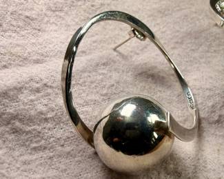 Sterling silver earrings designed in a modernist style, featuring circular hoops with a spherical accent. Marked ‘Mexico 925’, indicating its sterling silver composition. These earrings are designed with posts and butterfly back closures for secure wearing. Total approx. weight of 17.06 grams.