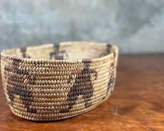 This lot features a stunning Native American basket, likely from the 1920s-1930s, made from heavy woven grass. This basket measures 3.75” H x 9.25” W x 6.5” D.