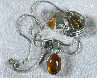This lot features a stunning ring and necklace made from sterling silver and featuring amber center stones. The ring comes in a size 7 and the chain measures, 17”. Both items have a total approx. weight of 25.00 grams.