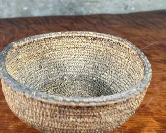 This lot features a turn of the century basket made of cedar root from the Cascades Plateau region, likely from the late 19th century or early 20th century. Measures, 3.5” H x 10” W x 10” D.