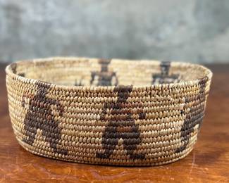 This lot features a stunning Native American basket, likely from the 1920s-1930s, made from heavy woven grass. This basket measures 3.75” H x 9.25” W x 6.5” D.