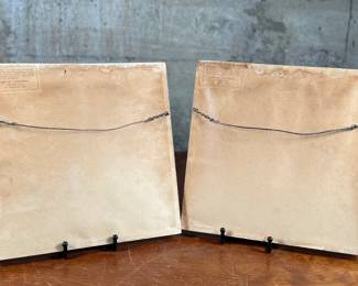 Two framed prints by Art of California, measuring 10.75” H x 10.75” W each. These are handcrafted reproductions of original paintings by Viennese artist Friedl, showcasing charming dance scenes with bright red backgrounds and decorative floral borders. Each piece is framed in light wood and features a paper backing with labeled production details.