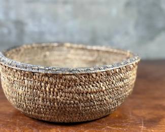 This lot features a turn of the century basket made of cedar root from the Cascades Plateau region, likely from the late 19th century or early 20th century. Measures, 3.5” H x 10” W x 10” D.