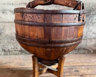 An antique Chinese wooden water bucket with stand. Features incredible patina through and well made. Measures on stand, 24” H x 18” W x 18” D.