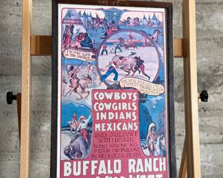Framed posters advertising the Buffalo Ranch Real Wild West show. Printed by Riverside Print Co., Chicago, these posters feature vibrant depictions of cowboys, Native Americans, and historical scenes. The frames show some age-related wear, and the paper backing is partially torn, exposing an art gallery label from Hulmeville, Pennsylvania. One of them is protected by glass and the other is not. Each one measures in frame, 37” H x 14.5” W.