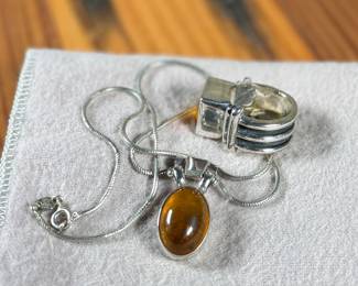 This lot features a stunning ring and necklace made from sterling silver and featuring amber center stones. The ring comes in a size 7 and the chain measures, 17”. Both items have a total approx. weight of 25.00 grams.