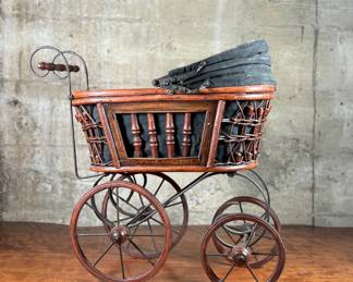 This lot features a beautiful antique Victorian-style doll carriage made from wicker, wood, and metal. This piece measures, 17.5” H x 19” W x 7” D.