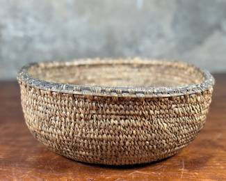 This lot features a turn of the century basket made of cedar root from the Cascades Plateau region, likely from the late 19th century or early 20th century. Measures, 3.5” H x 10” W x 10” D.