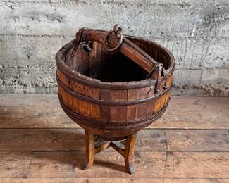 An antique Chinese wooden water bucket with stand. Features incredible patina through and well made. Measures on stand, 24” H x 18” W x 18” D.