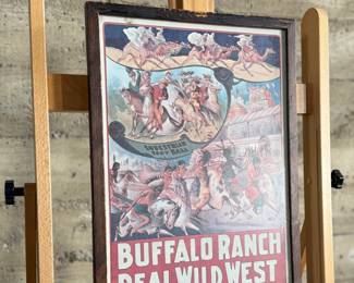 Framed posters advertising the Buffalo Ranch Real Wild West show. Printed by Riverside Print Co., Chicago, these posters feature vibrant depictions of cowboys, Native Americans, and historical scenes. The frames show some age-related wear, and the paper backing is partially torn, exposing an art gallery label from Hulmeville, Pennsylvania. One of them is protected by glass and the other is not. Each one measures in frame, 37” H x 14.5” W.