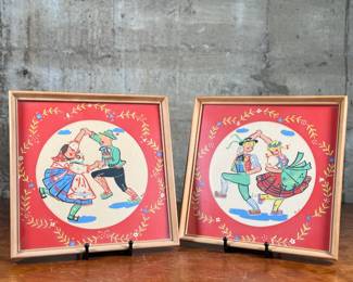 Two framed prints by Art of California, measuring 10.75” H x 10.75” W each. These are handcrafted reproductions of original paintings by Viennese artist Friedl, showcasing charming dance scenes with bright red backgrounds and decorative floral borders. Each piece is framed in light wood and features a paper backing with labeled production details.