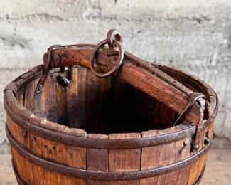 An antique Chinese wooden water bucket with stand. Features incredible patina through and well made. Measures on stand, 24” H x 18” W x 18” D.