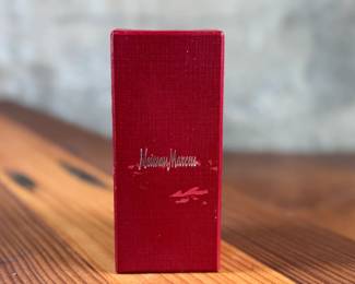 Silver-toned wine stopper adorned with intricate detailing, presented in its original Neiman Marcus red box. The stopper features a decorative design and includes a rubberized insert for a secure fit. Box measures approximately 4 inches in length. Appears to be in excellent condition with minimal wear on the packaging.